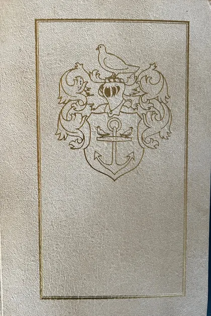 Forside av slektsboka fra 1974, lyst skinn med gullpreget våpenskjold og dobbel gullramme